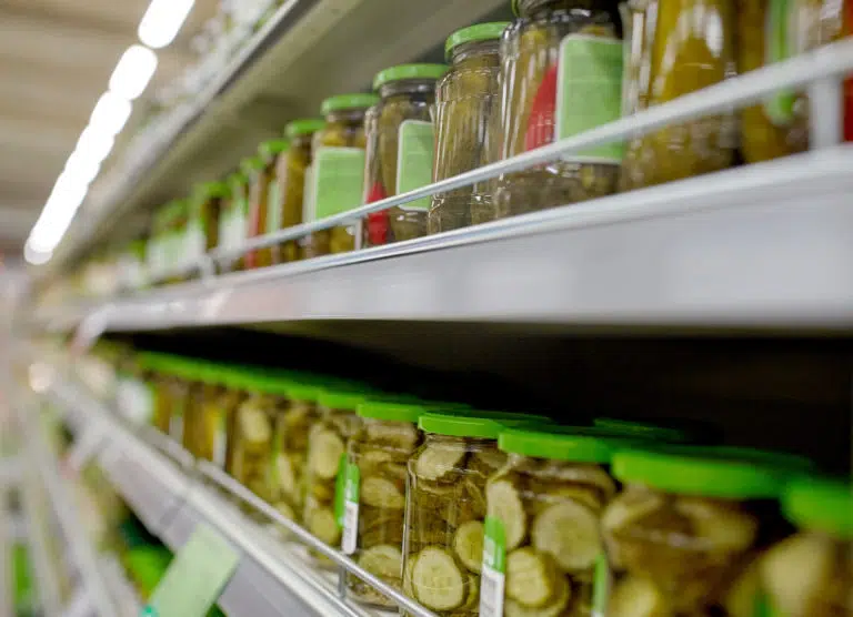 A shelf filled with pickles and other food.