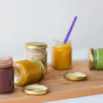 A wooden board with jars of different kinds of food.